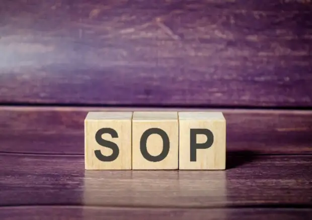 wooden blocks spelling the word sop on a wooden surface